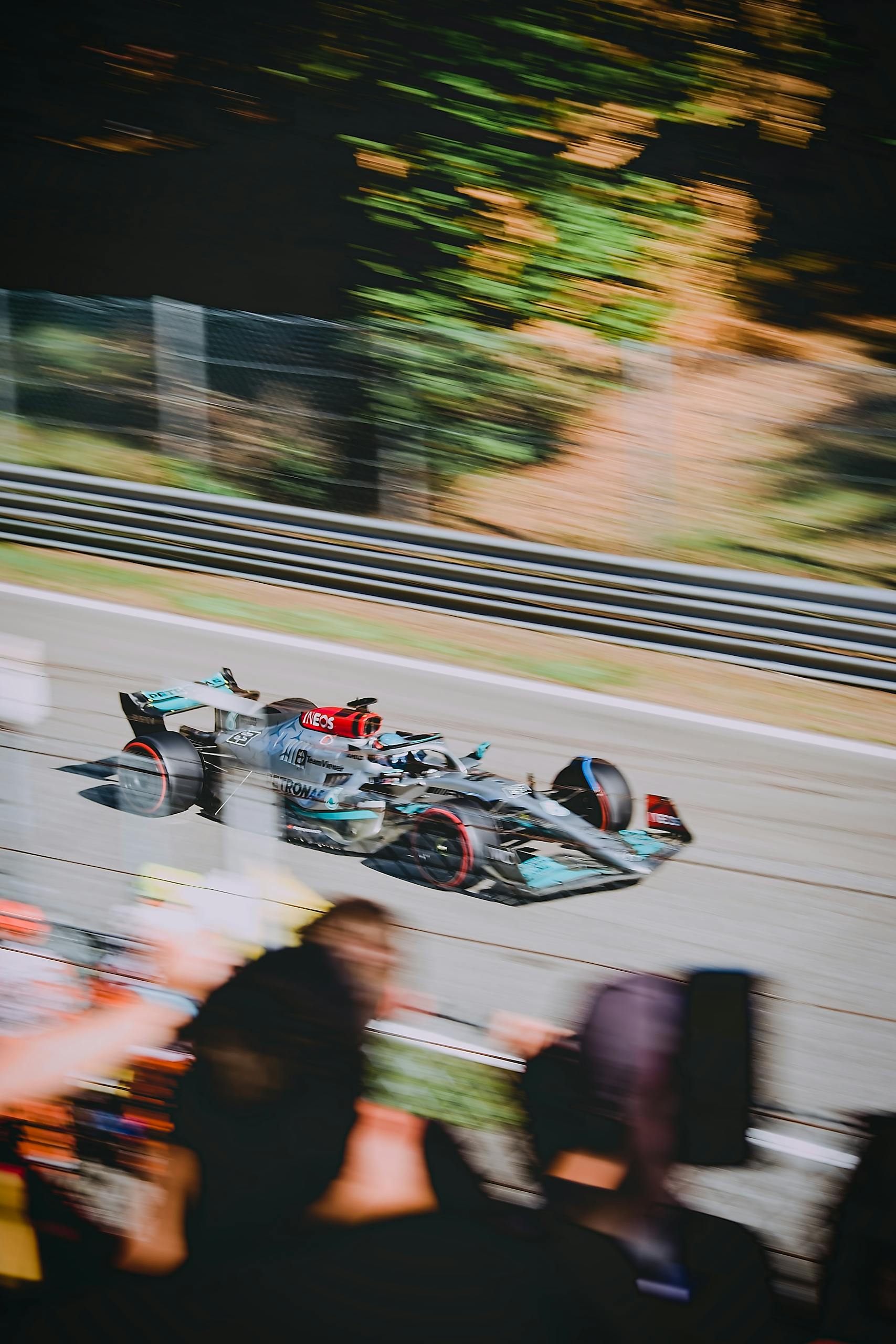 Blurred motion Formula 1 car racing on outdoor track with spectators watching the thrilling motorsport event.