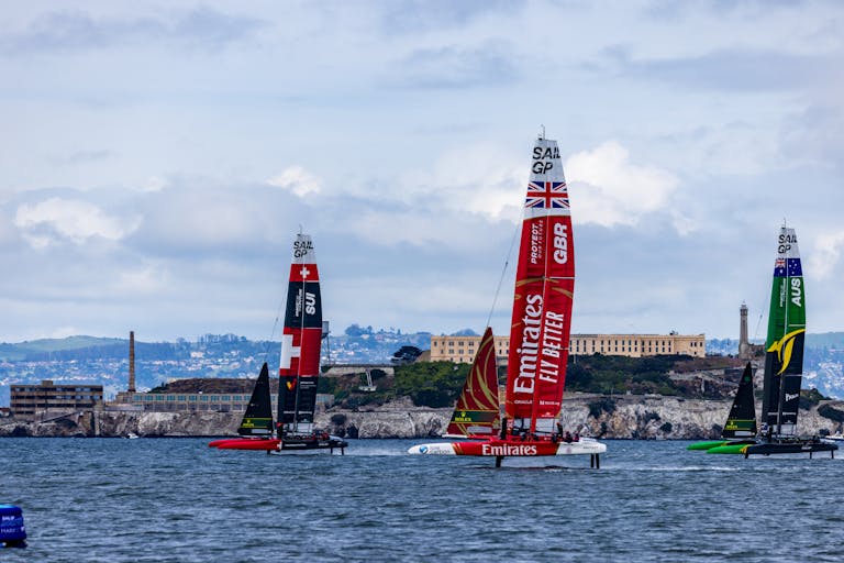 Catamarans racing in San Francisco Bay with Alcatraz Island in the background during a sailing event.